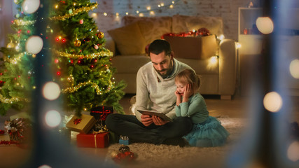 Looking Through the Window. Father Reads Book to His Daughter, Sitting Under Christmas Three with...