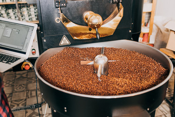 Freshly roasted aromatic coffee beans over a modern coffee roasting machine.