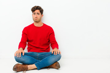 young handsome man feeling sad and whiney with an unhappy look, crying with a negative and...