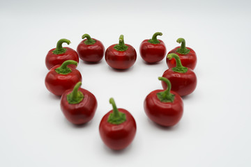 Shape of heart, red hot chili peppers isolated on white background. Ripe peppers, spicy vegetables