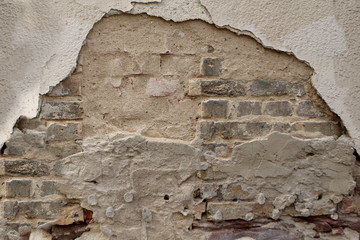 texture of an old brick wall with crumbling and cracked stucco, background