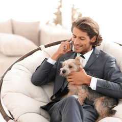 businessman is holding his pet and talking on a smartphone