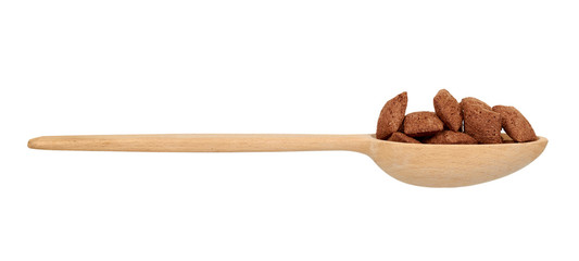 Chocolate pillow cereal, breakfast food. Crunchy snack with oat and corn. Wooden spoon.