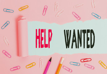 Handwriting text writing Help Wanted. Conceptual photo An ad in the paper an employer places to find a new employee Stationary and torn cardboard placed above a plain pastel table backdrop