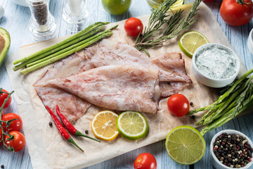 photo seafood and fish on parchment with vegetables on the Board