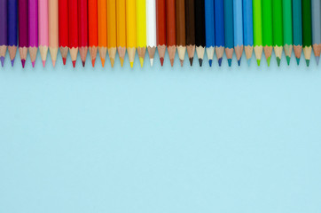 Fototapeta premium Colored pencils composition on blue background. Flat lay.