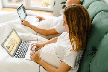 Obraz premium Young people at home or millennial beautiful couple in the hotel using internet connection and technology devices like computer laptop