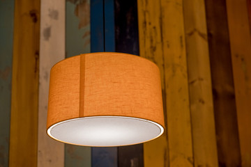 modern orange lamp with vintage light bulb.stylish lamps on wooden background.colorful wall,...
