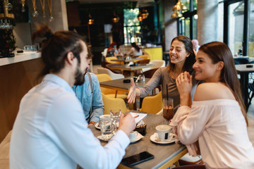Two young men meet two young women in a cafe