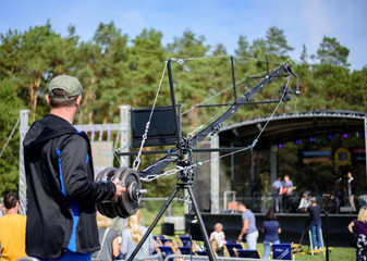 Video camera operator working with his Cine Camera Crane at outdoor event