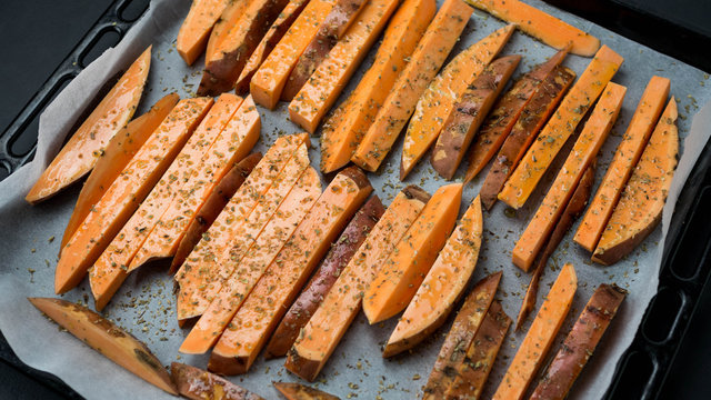 Pokrojone bataty leżące na blasze. Przygotowanie frytek. Widok z g&oacute;ry.