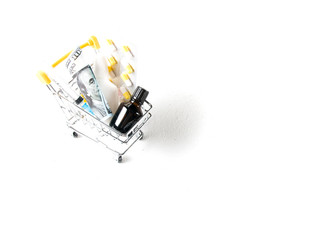 pharmacy,medicines and dollars in a shopping trolley and mercury thermometer on a white background copy space