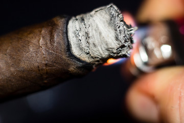 close up of a Cuban cigar being lit with a flame 