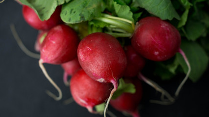 Pęczek rzodkiewki, świeże warzywa leżące na ciemnym tle. Zbliżenie.