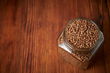 Fototapeta na wymiar buckwheat in a jar closeup on a brown wood background