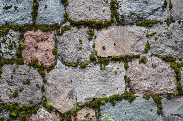 close-up of a wall background made of old stones overgrown with moss