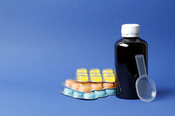 Bottles of cough syrup and  Blisters with color cough drops  blue background