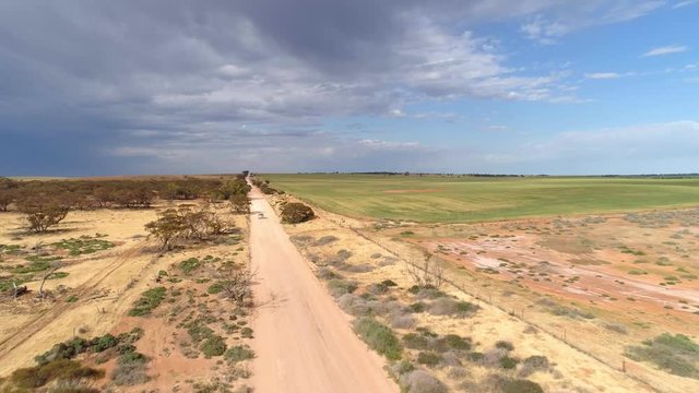 Forwad flight tracking shot of car driving on rural road in Australian outback