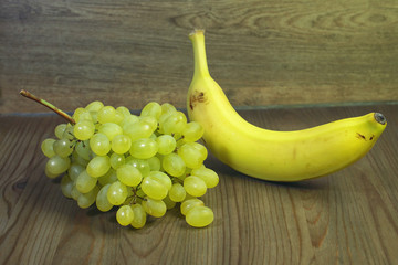 bunch of grapes and a banana on a wooden background