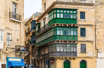 Fototapeta premium Residential house facade with traditional Maltese multicolored enclosed wooden balconies in Valletta, Malta, in summer day. Authentic Maltese urban scene.