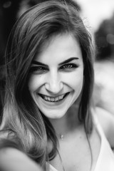 Monochrome portrait of attractive girl with european features, wide smile and happy eyes. Girl wearing in blouse and silver accessories looking at camera. Concept of fashion and vogue.