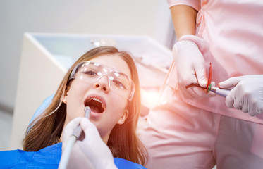 Attractive young woman in stomatology clinic with male dentist. Healthy teeth concept.