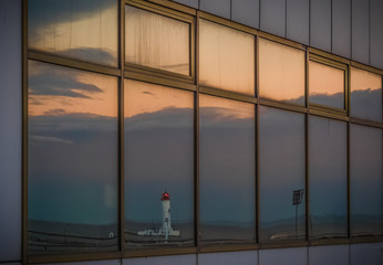 White lighthouse in port window reflection.
