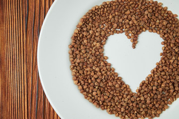 buckwheat heart symbol in a white plate on a wooden background