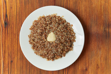 boiled buckwheat in a white plate on a wooden background