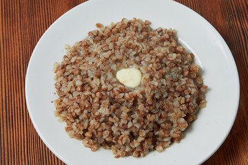 boiled buckwheat in a white plate on a wooden background