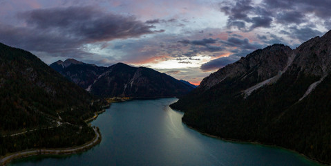 sunrise at lake plansee with red cloudy sky in tyrol mountains