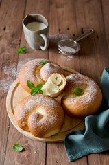 Buns with powdered sugar and milk on a wooden table