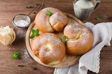 Buns with powdered sugar and milk on a wooden table
