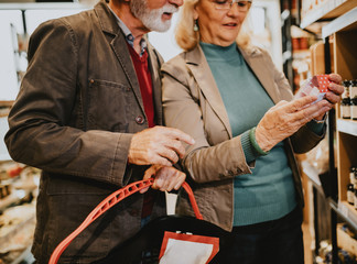 Happy senior couple shopping in grocery store or supermarket. Consumerism concept.