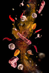 Hot red pepper, garlic, different spices powder meat stakes flying on a black background Motion freeze photo composition © Vitte Yevhen