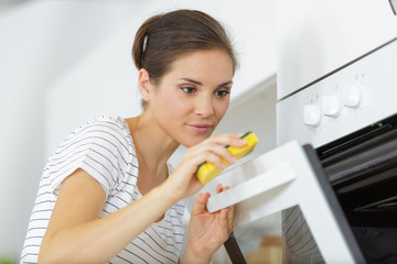 happy woman cleaning cooker at home kitchen