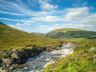 Fototapeta na wymiar Scottish nature in Isle of Skye with blue sky background and creek valley