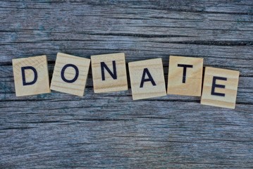 Fototapeta premium word donate made of wooden letters on a gray table