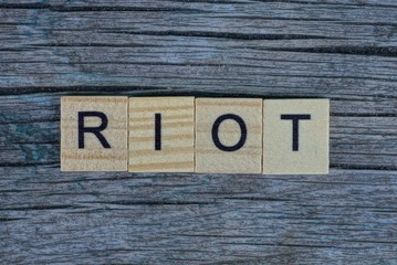 word riot of brown wooden letters on a gray table