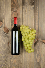 Botella de vino y racimo de uvas verdes en la mesa