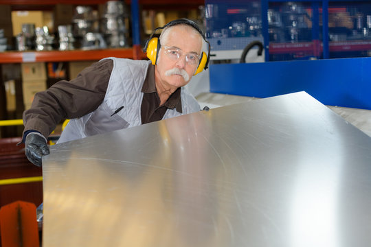 senior working with metal sheets at a factory - Powered by Adobe