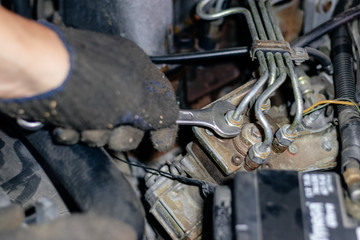 Man mechanic works in the garage. Repairs the engine of an old car