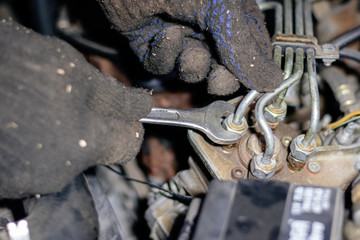 Man mechanic works in the garage. Repairs the engine of an old car