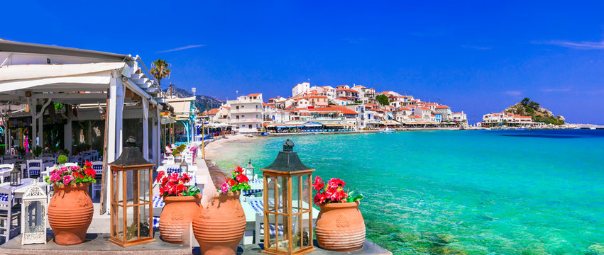 Kokkari Samos 11k panorama of traditional Greek tavern with clay pots and flowers. Scenic Aegean sea view of empty beach and authentic village in Greece. Mediterranean summer travel scenery