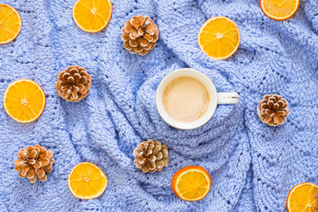 Winter coffee on blue blanket with pine cones and dry oranges. Top view, flat lay