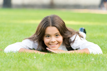 Keep calm and relax. Happy child with school look lying on green grass. Little girl smile with formal fashion look. Beauty look of small schoolchild