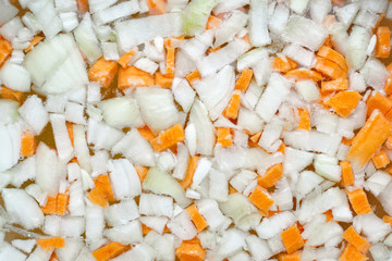 Cooking vegetable soup. Chopped ​​onion and carrot pieces in boiling water in a pan. Food background