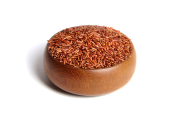 Red rice in a brown wooden bowl isolated on white background. Dry uncooked cereal grains, ingredient for cooking  various dishes