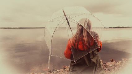 Girl on the lake with an umbrella in bad weather
