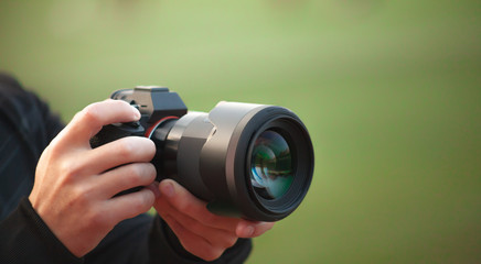Photographer men shooting images. Man hands holding camera taking photos. Vivid blur green background